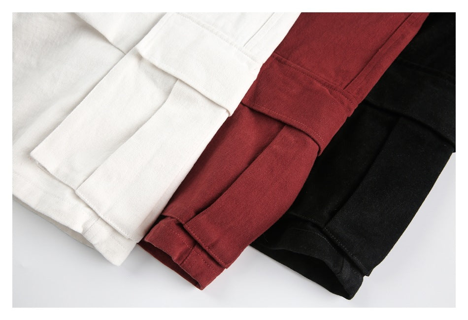 Close-up of folded ivory, burgundy, and black trouser legs showing stitched hems.