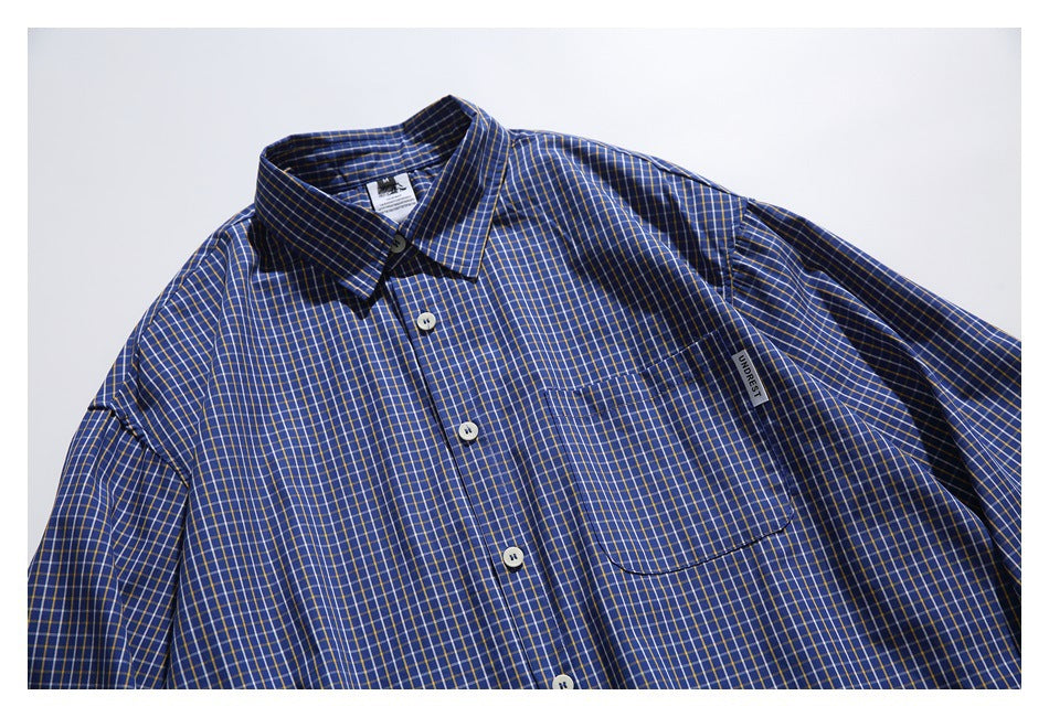 Close-up of the blue checked shirt's front, collar, button placket, chest pocket, and small sewn label.