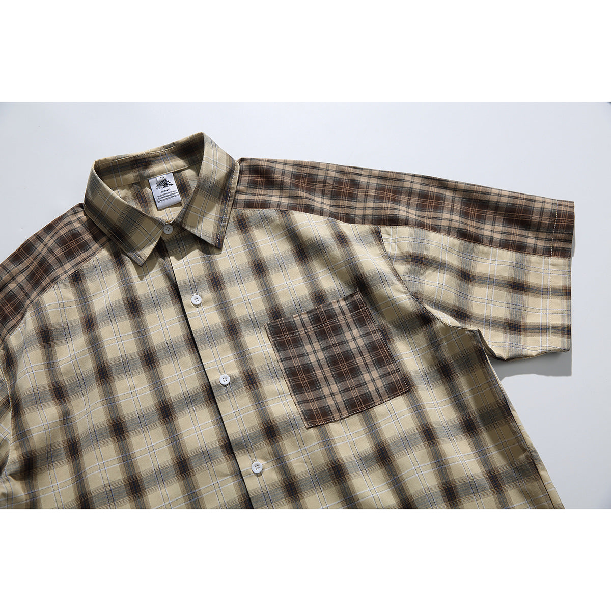 Tan plaid short-sleeve button-up shirt laid flat, with a contrasting brown plaid chest pocket.