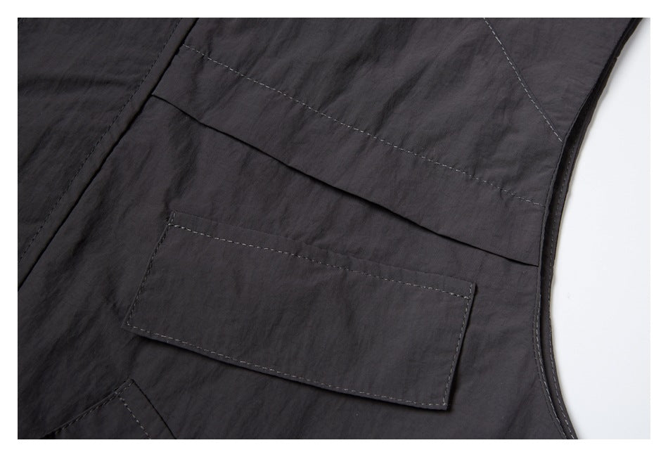 Close-up of layered pockets and contrast stitching on the charcoal vest.