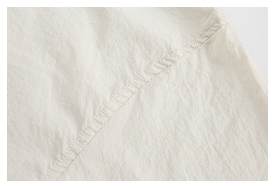 Close-up of cream fabric showing a curved stitched seam and softly crinkled texture.