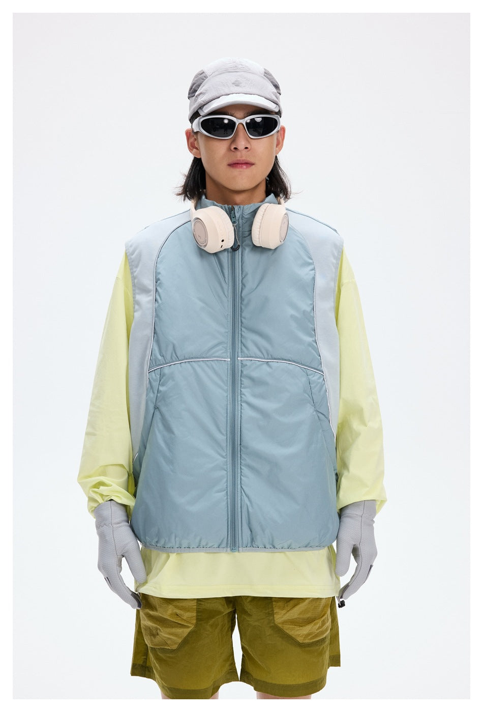 Front view of a cyclist wearing a pale blue zip-front vest with light reflective trim.