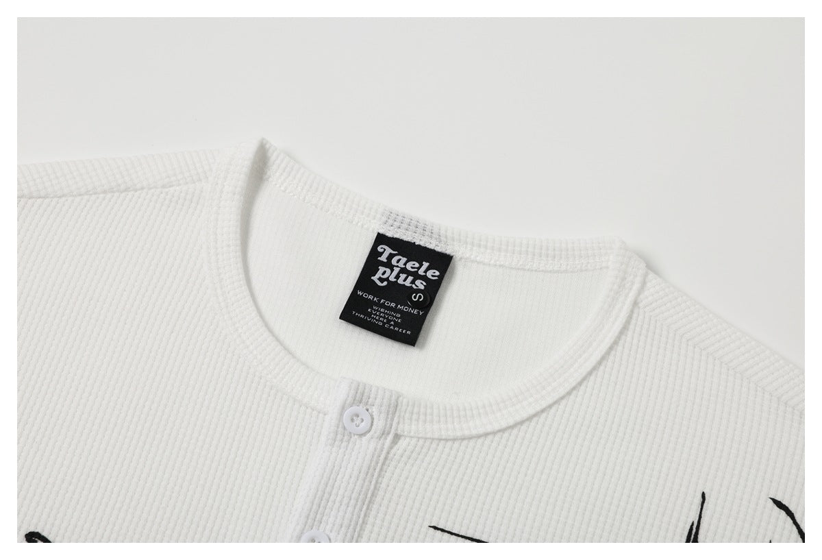 Close-up of a white button-front top's round neckline, white button, and sewn black neck label.