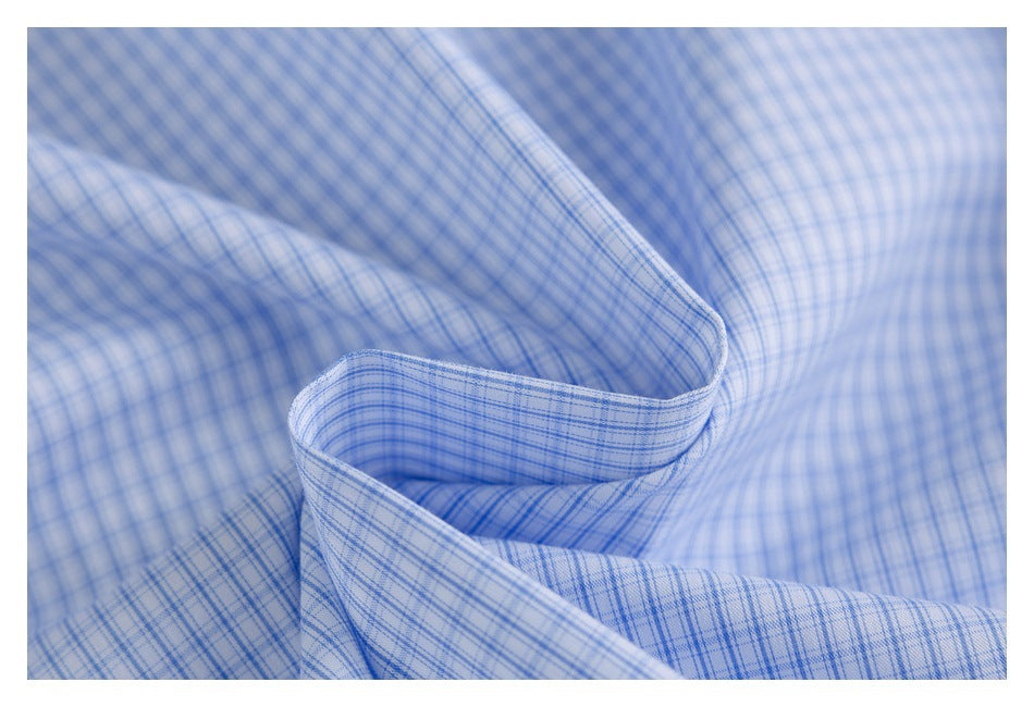 Close-up of light blue and white fabric with a fine blue plaid pattern and soft folds.
