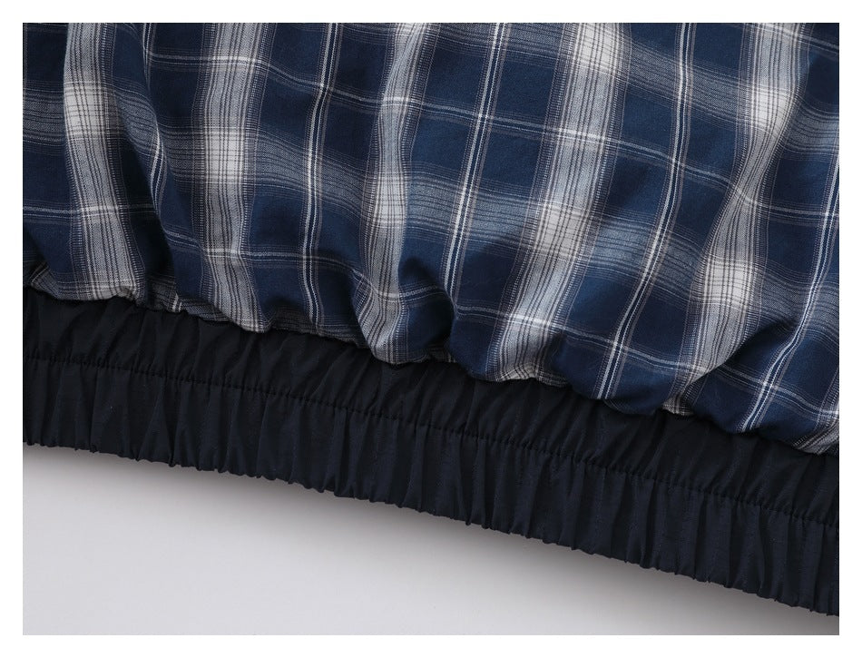 Close-up of blue-and-white plaid fabric above a gathered black elastic hem.