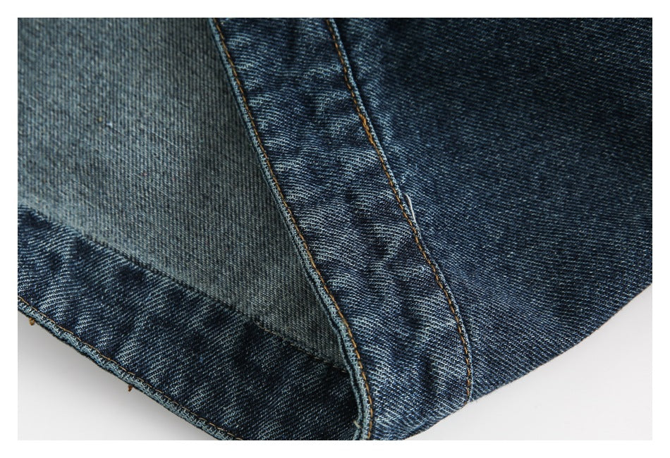 Close-up of a dark blue denim jacket hem and stitched panel edge.