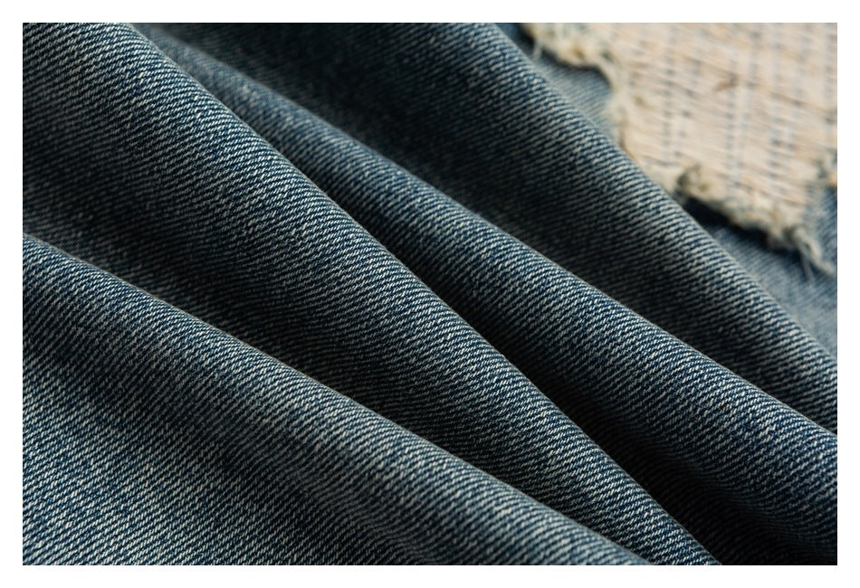 Close-up of dark blue denim fabric arranged in soft folds, showing its diagonal weave.