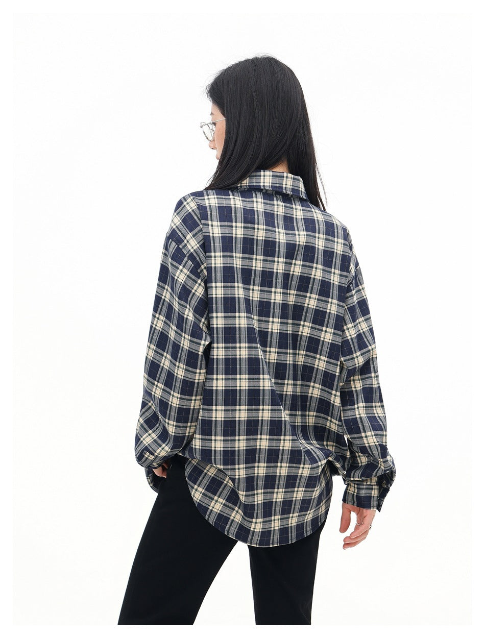 Rear view of a model wearing a navy and cream plaid shirt with a rounded hem.