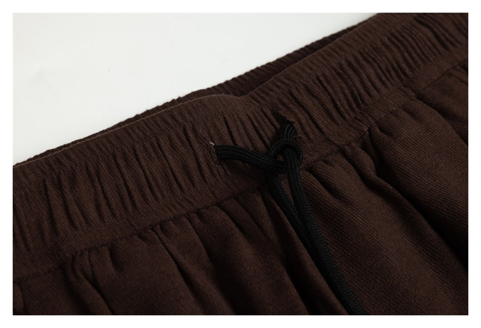 Close-up of the gathered waistband and black drawstring on dark brown pants.