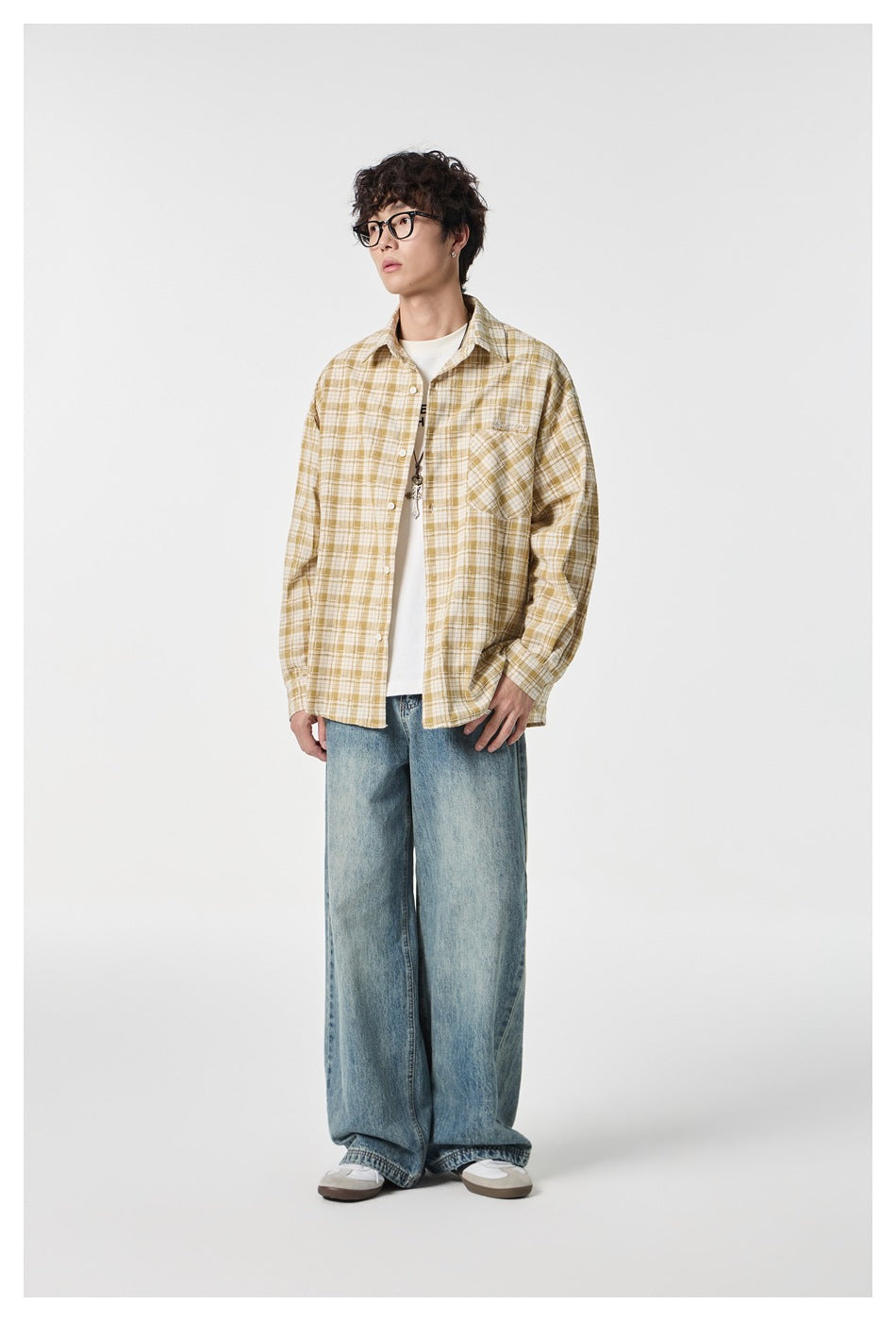 Full-length view of a model wearing a mustard and cream plaid button-up shirt with loose blue jeans.