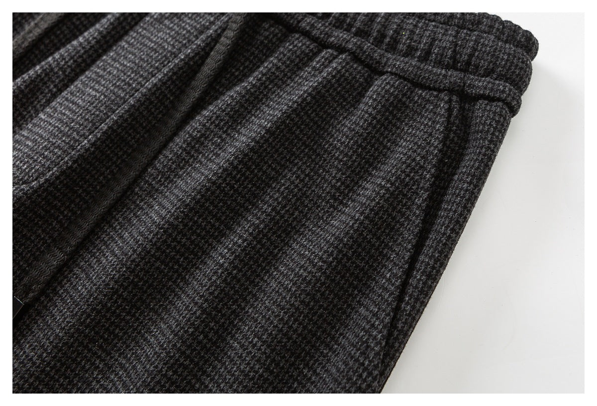 Close-up of charcoal gray patterned trousers showing the elastic waist and a pocket seam.