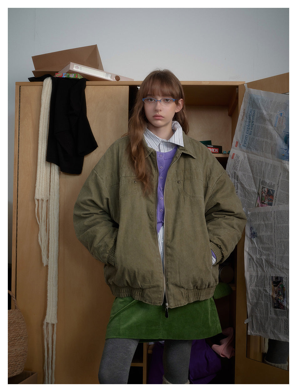 Model wearing an army green oversized collared zip-front jacket with hands in pockets, styled with a green skirt