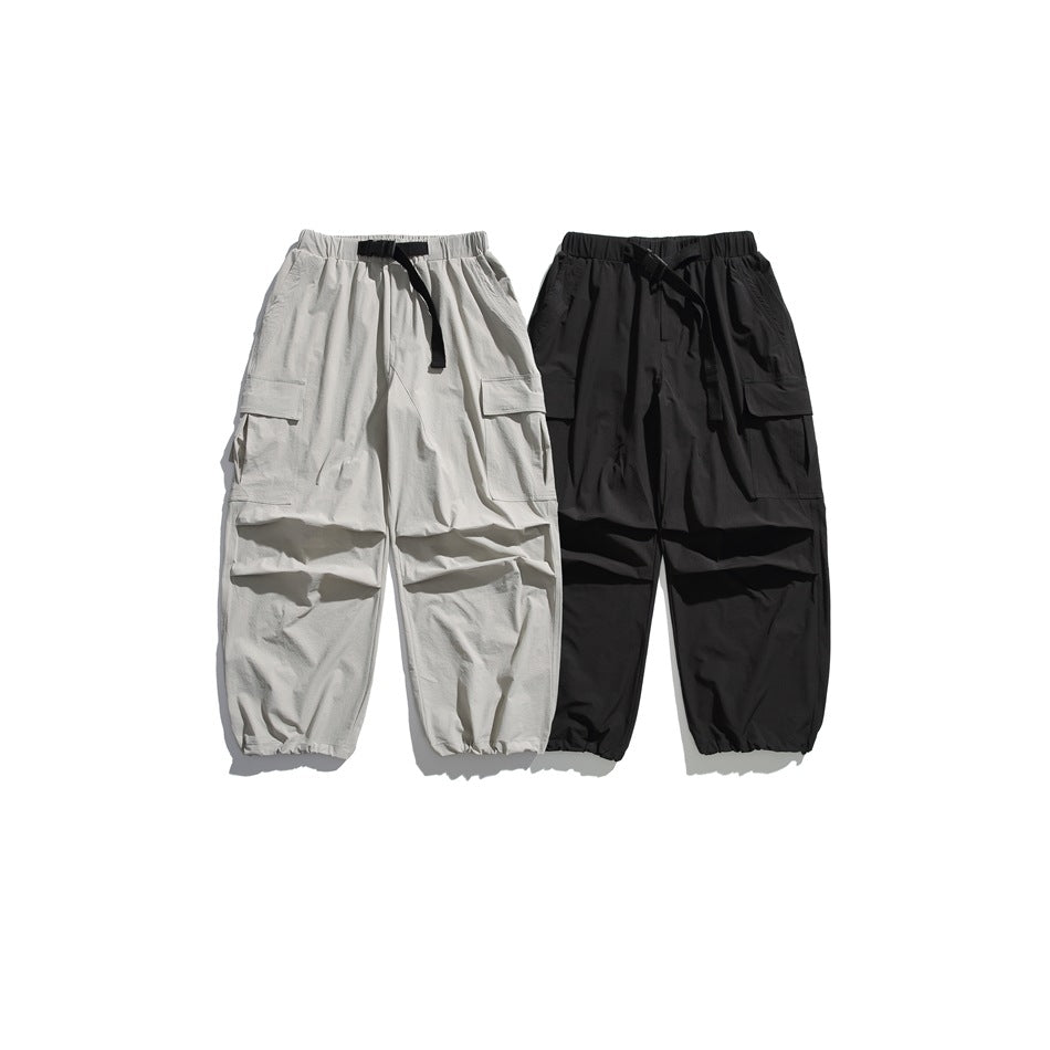 Two pairs of loose cargo pants displayed flat against white: one light gray and one black.