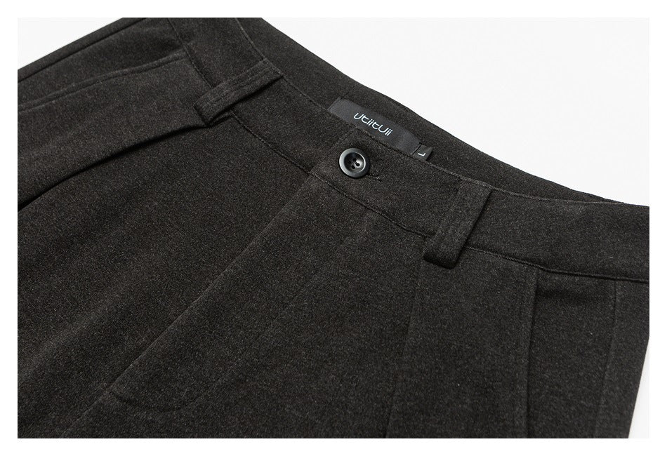 Close-up of dark brown trouser waistband with button, belt loops, and a sewn-in label.