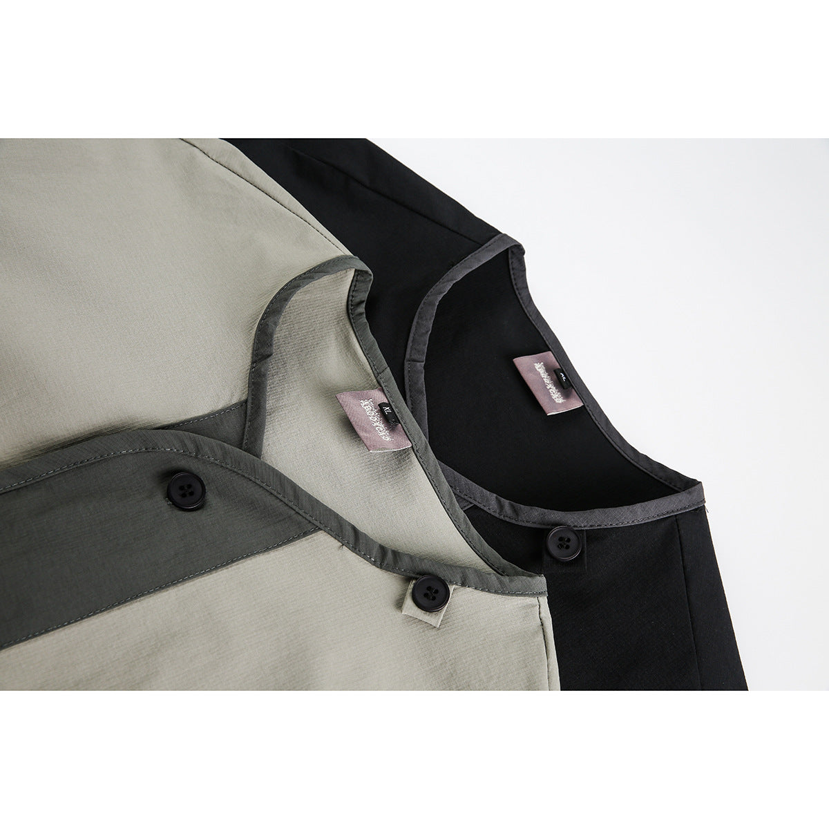 Close-up of beige and black shirts showing contrasting dark trim, buttons, and neckline labels.