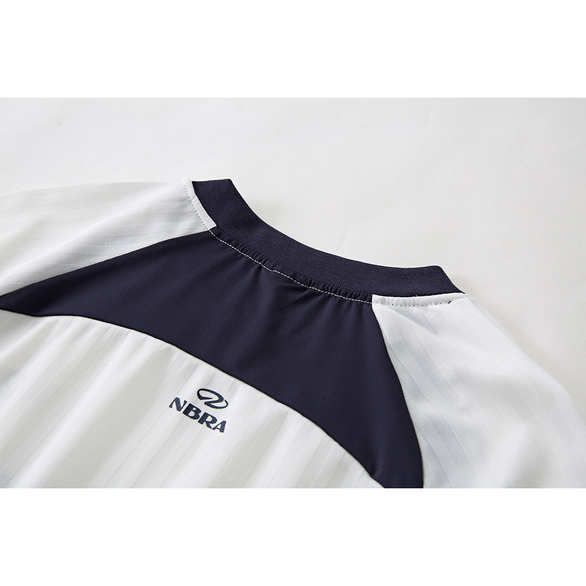 Close-up of the jersey back showing a navy yoke between white pinstriped panels and a small logo.