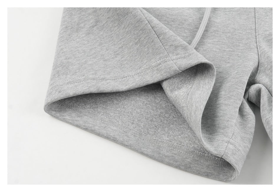 Close-up of the stitched hem and leg opening of light gray sweatpants.