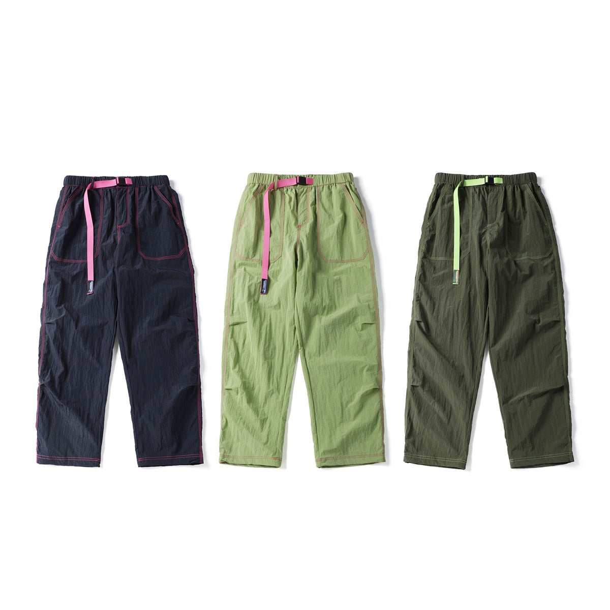 Three front views of relaxed pants in navy, light green and dark olive, each with contrast stitching and a belt.