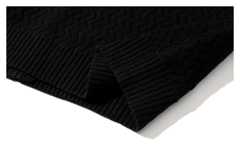 Close-up of a black knit garment showing a ribbed edge and seam.