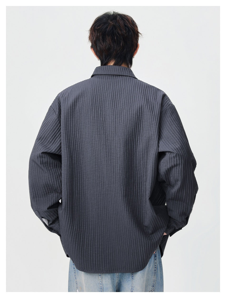 Back view of a model wearing an oversized charcoal ribbed button-up shirt with a rounded hem.
