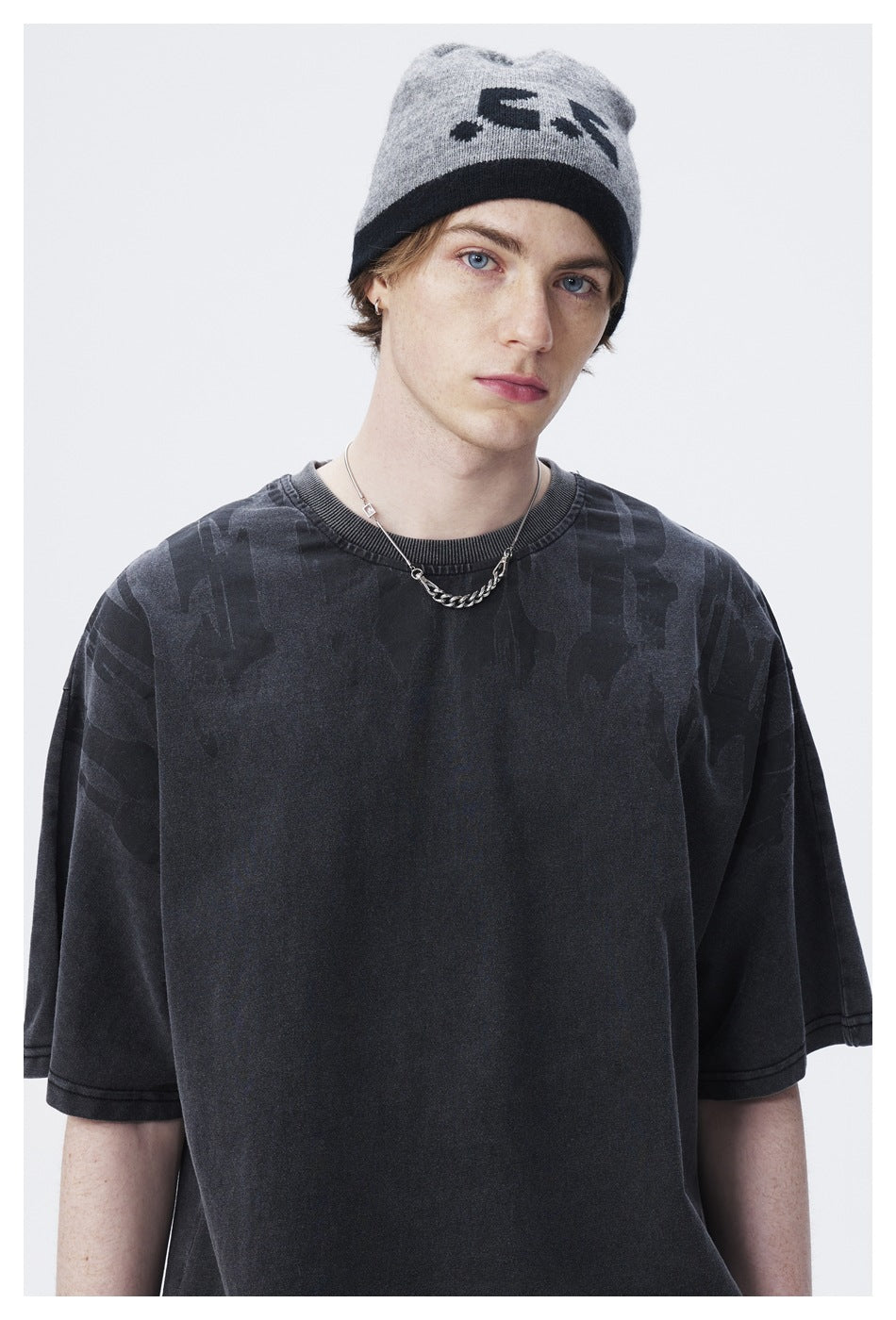 Close view of a model wearing a charcoal T-shirt with subtle tonal shoulder graphics and a ribbed crew neck.