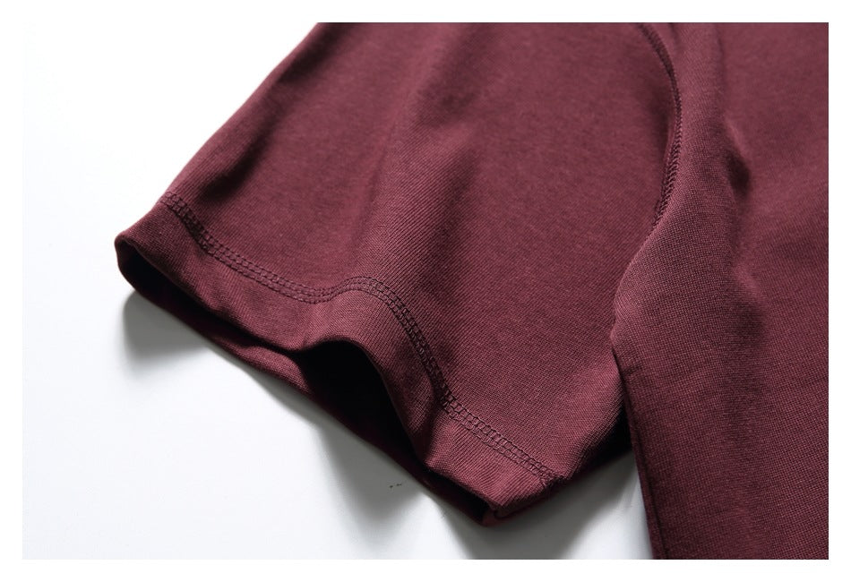 Close-up of a burgundy shirt sleeve showing its folded edge and double-row stitching.