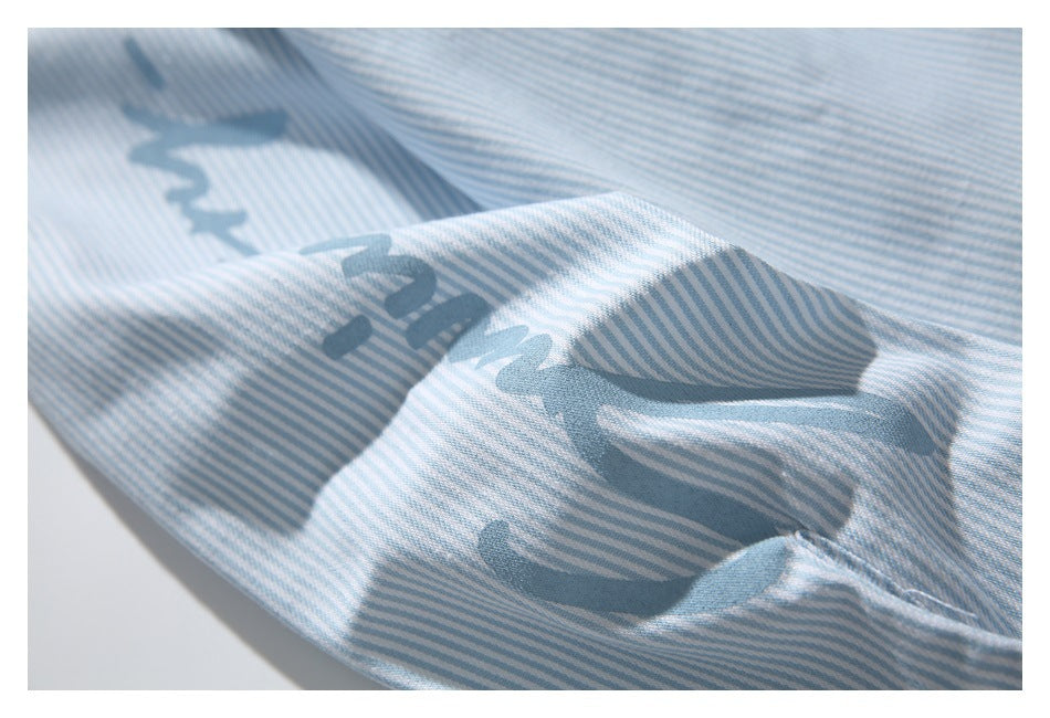 Close-up of blue lettering printed across a light blue and white striped shirt.