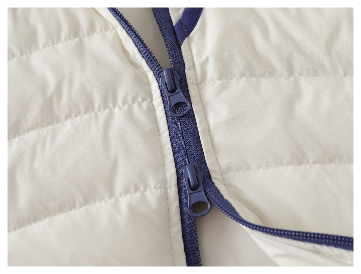 Close-up of an ivory quilted garment with a navy two-way zipper and matching trim.