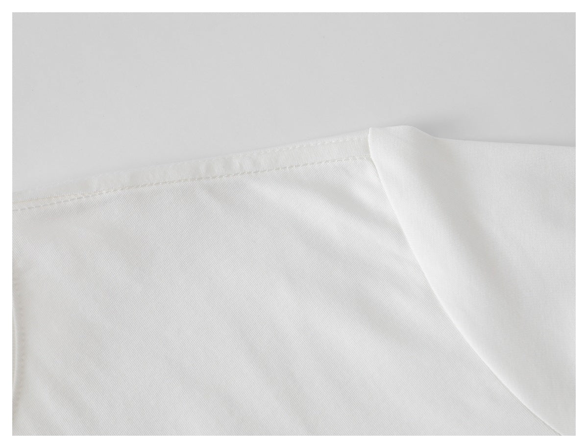 Close-up of a white T-shirt's shoulder seam and sleeve on a light background.