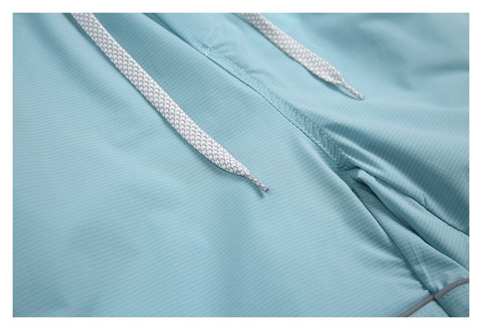 Close-up of the white drawstrings, center seam, and contrast piping on the light blue shorts.