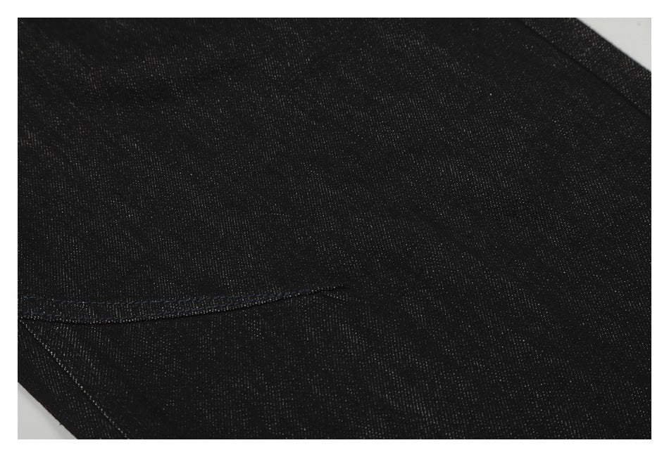 Close-up of black denim showing its fine woven texture and a dark seam.