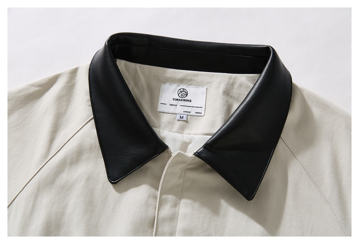 Close-up of an ivory jacket with a wide black collar and a sewn neck label.