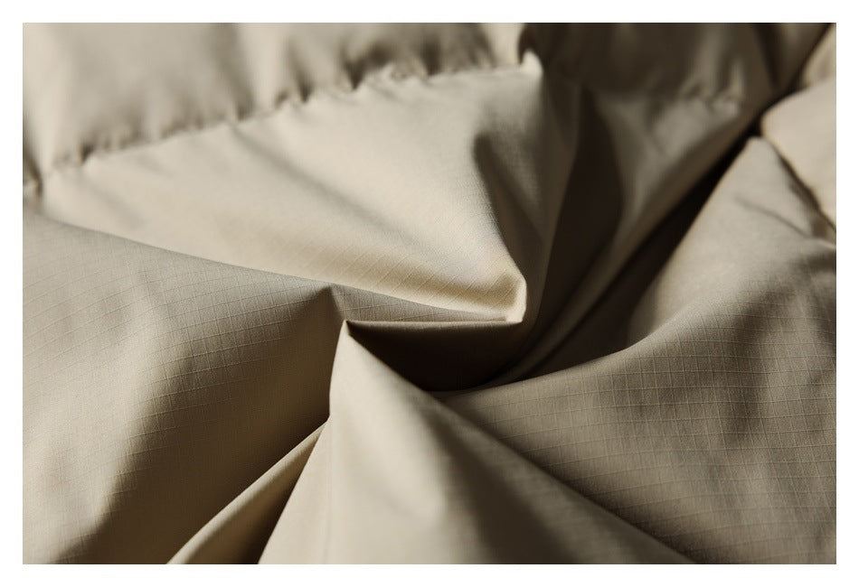 Close-up of beige jacket fabric showing a fine grid texture and stitched seams.