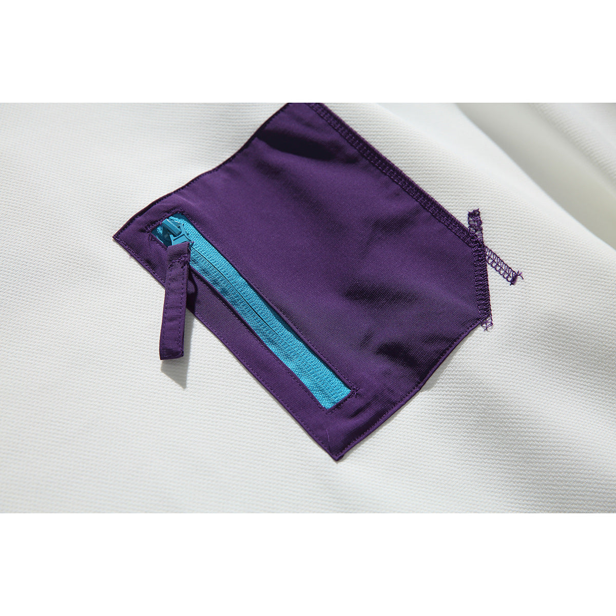 Close-up of the sweatshirt’s purple chest pocket with a bright cyan zipper and purple pull tab.