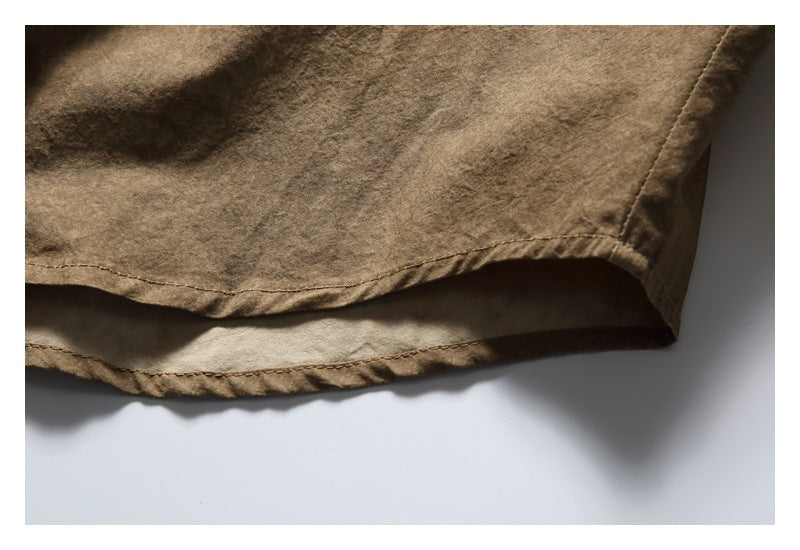 Close-up of the curved hem and stitching on a brown shirt.