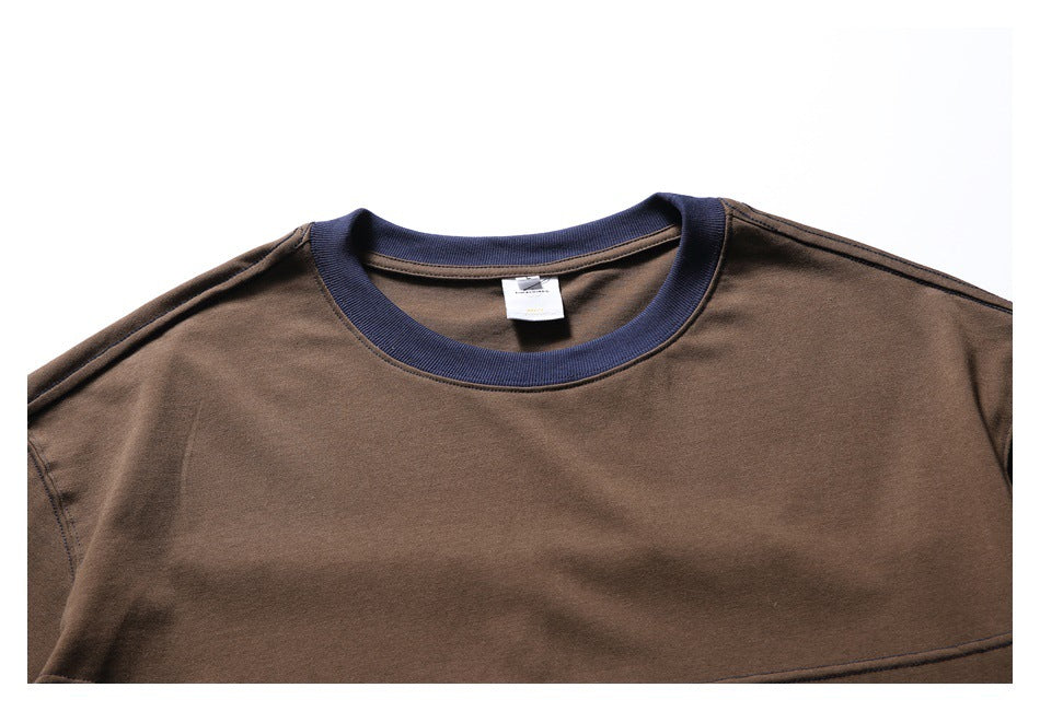 Close-up of the brown T-shirt front showing its navy ribbed crew neck and upper chest seam.