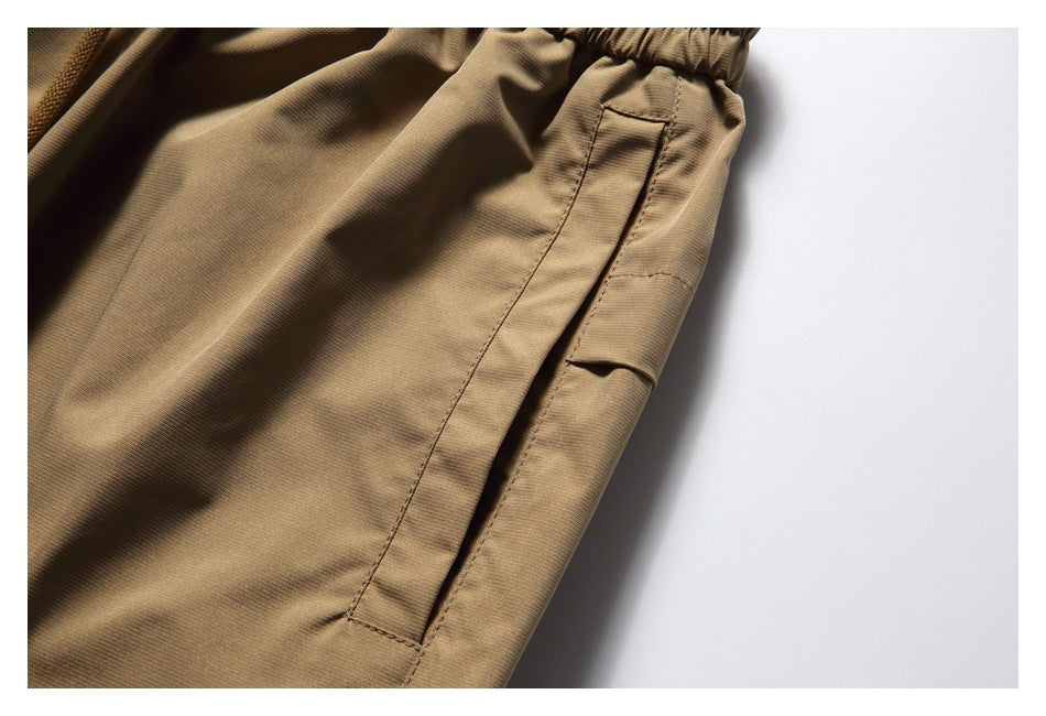 Close-up of a tan cargo pants side pocket with a flap and stitched seams.