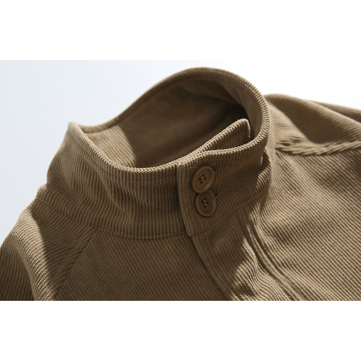 Close-up of a tan corduroy jacket's raised collar with two brown buttons.