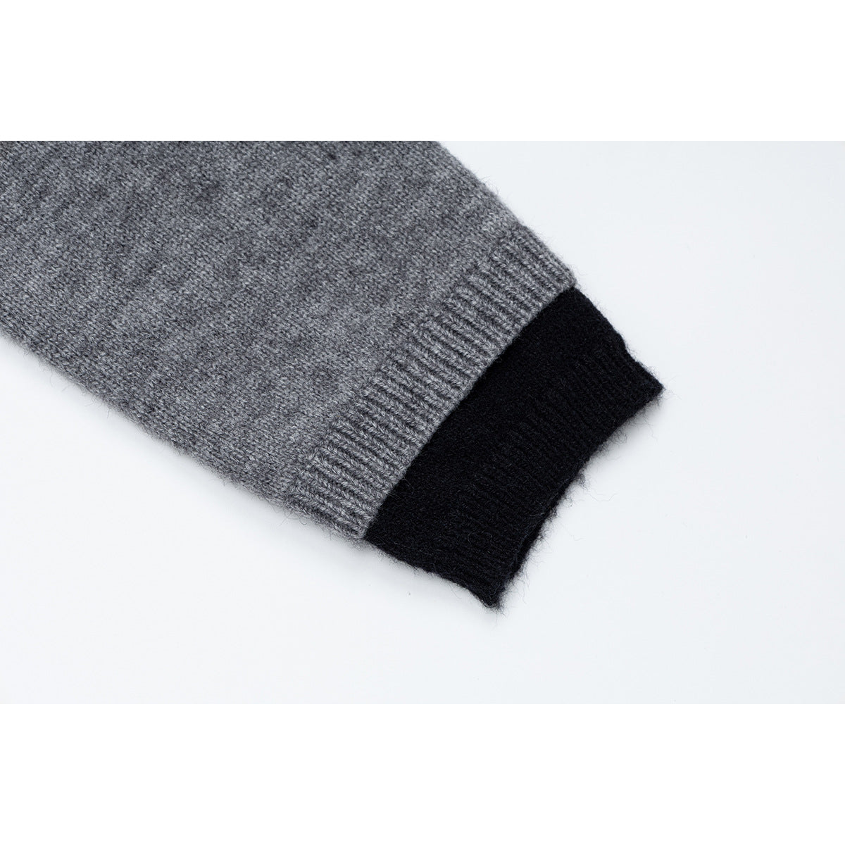 Close-up of a gray knit cardigan sleeve cuff with a ribbed gray band and black contrasting trim.