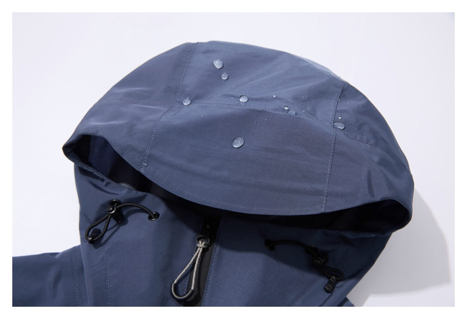 Close-up of a slate-blue jacket hood with water droplets, black drawcord toggles, and a central zipper.