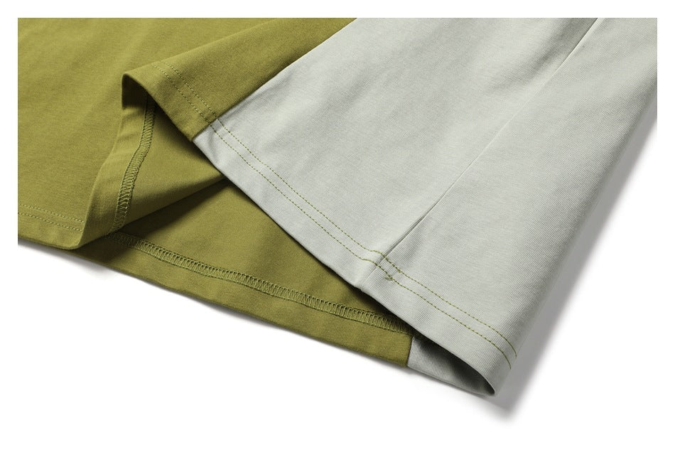 Close-up of the olive-green shirt hem beside a light gray panel, showing stitching and overlocked seams.