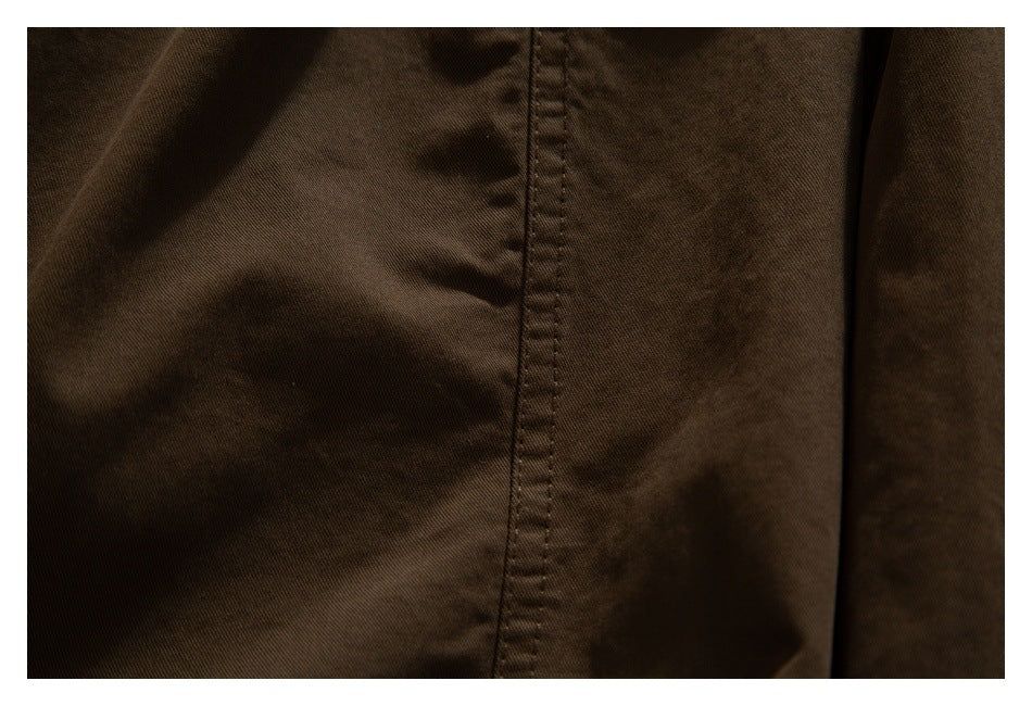 Close-up of dark brown fabric with a vertical stitched seam and soft folds.