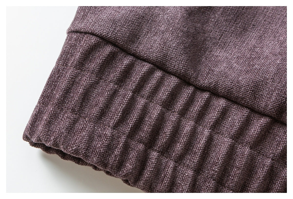Close-up of a gathered cuff or hem on plum textured fabric.