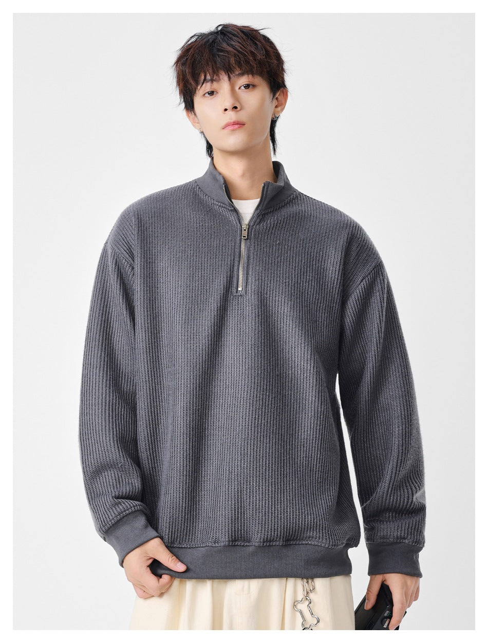 Model wearing a charcoal gray textured quarter-zip sweater with a stand collar, ribbed cuffs and hem.