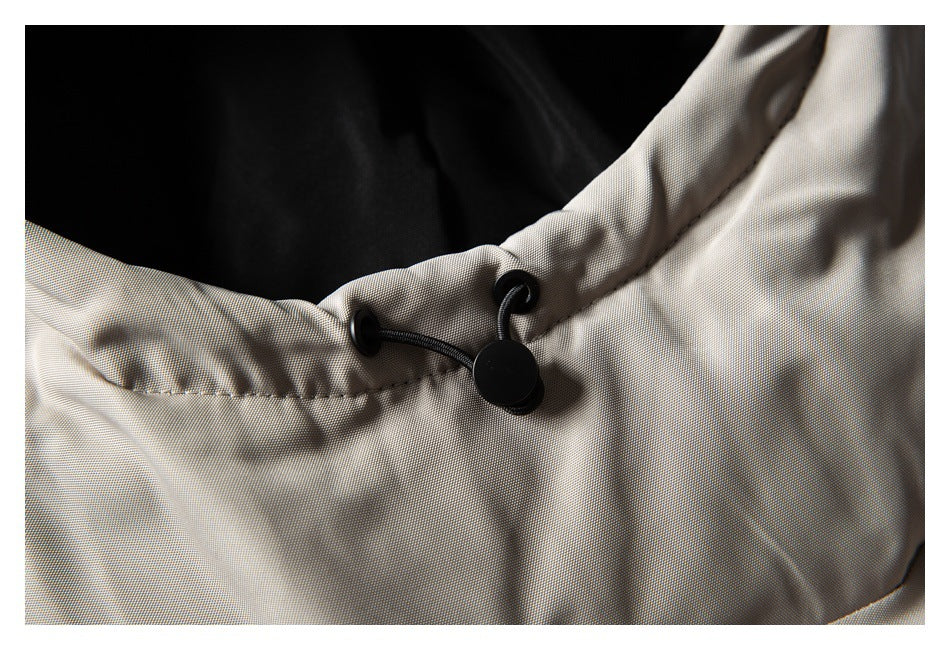 Close-up of a black drawcord toggle on the beige garment’s edge, with black fabric behind it.
