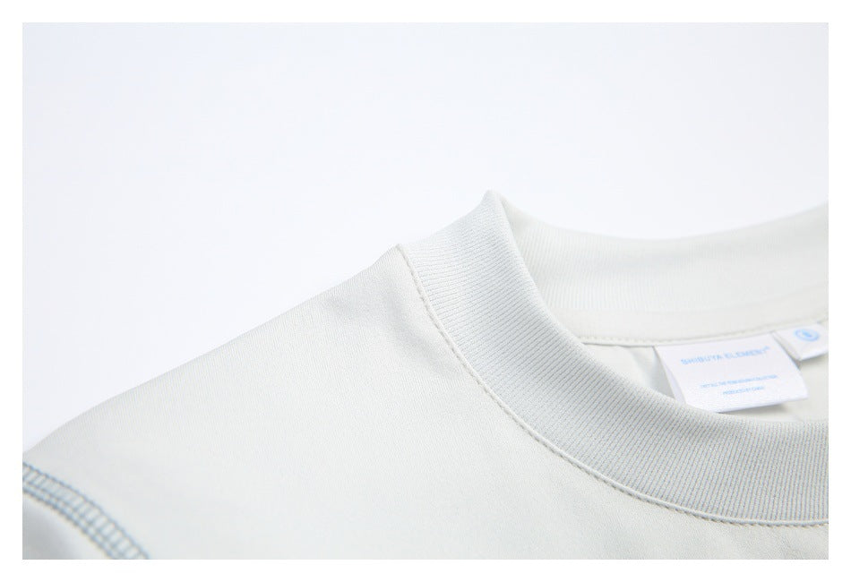 Close-up of an off-white shirt's ribbed crewneck and shoulder seam, with a small inside neck label.