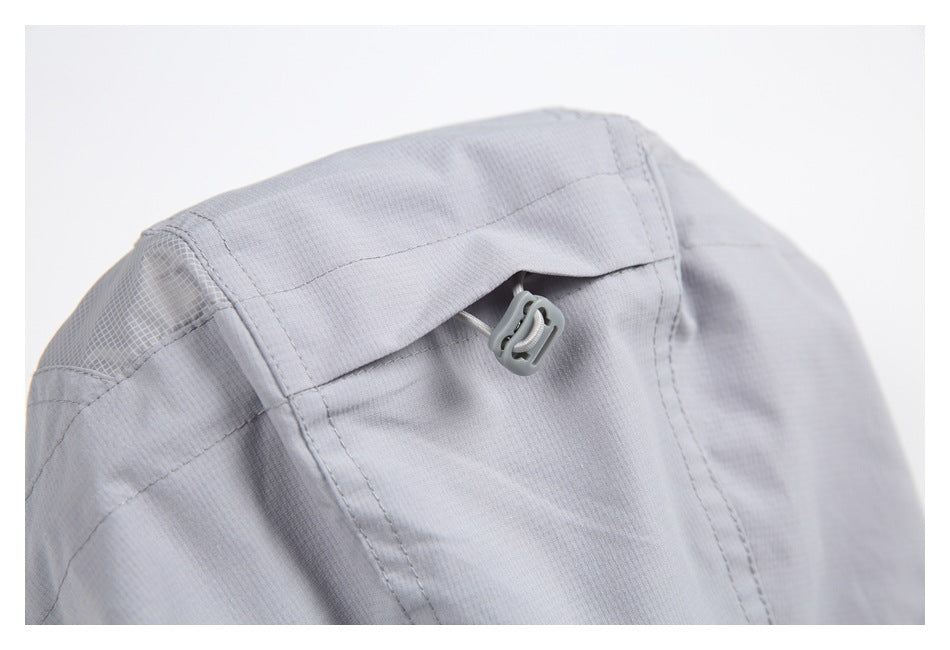 Close-up of a light gray jacket hood with an adjustment toggle and stitched panels.