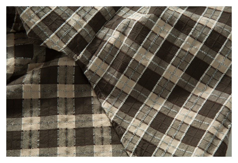 Close-up of overlapping brown and beige plaid garment panels and stitching.