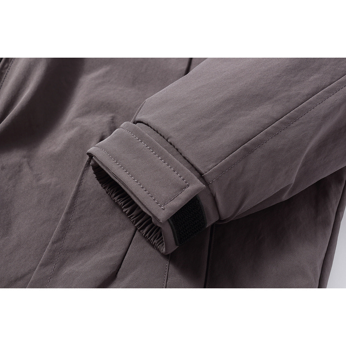 Close-up of a dark gray jacket sleeve cuff with an adjustable hook-and-loop tab.