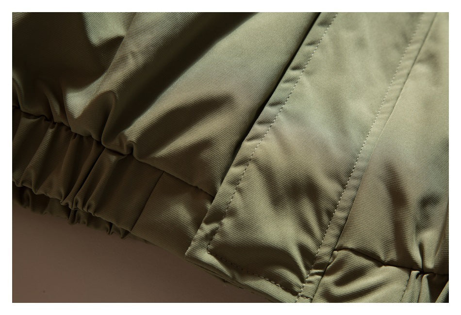 Close-up of olive-khaki garment with a gathered edge and a stitched panel.